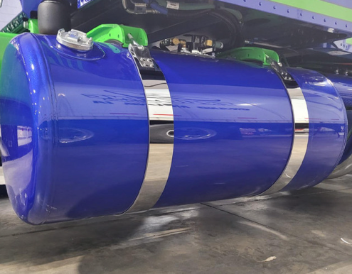 Iowa Customs 4-inch stainless steel fuel tank strap skins installed on a blue Peterbilt 389 — mirror-polished finish highlighting OEM fitment.