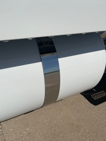 Installed Iowa Customs 4-inch stainless steel fuel tank strap skin on a white Peterbilt tank — polished mirror finish and clean OEM look.